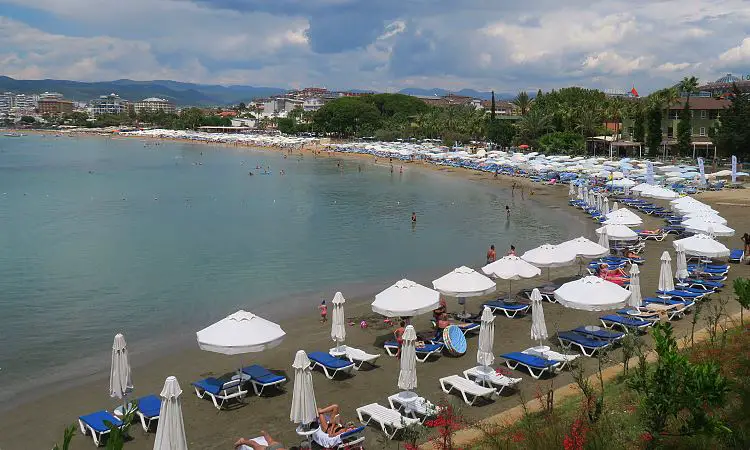 Urlauber liegen am Sandstrand auf Liegestühlen.