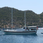 Eine weiße Segelyacht mit zwei Masten ist vor der Insel Kekova zu sehen.