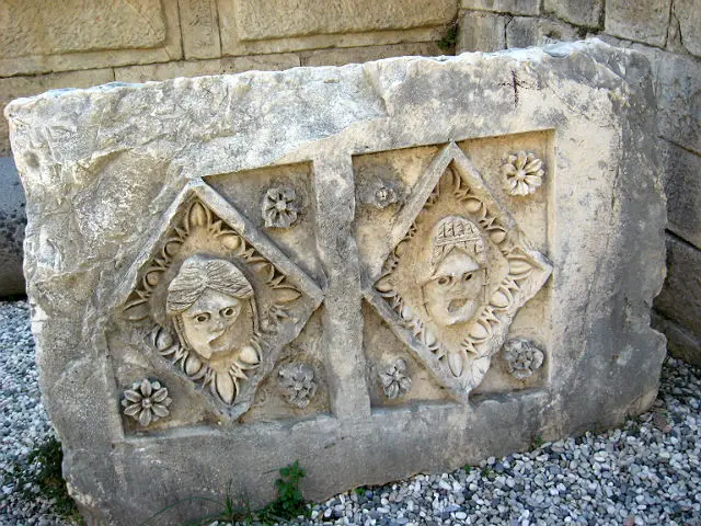 Relief auf einem ausgegrabenen Mauerstein Relief mit zwei Gesichtern auf einem ausgegrabenen Mauerteil