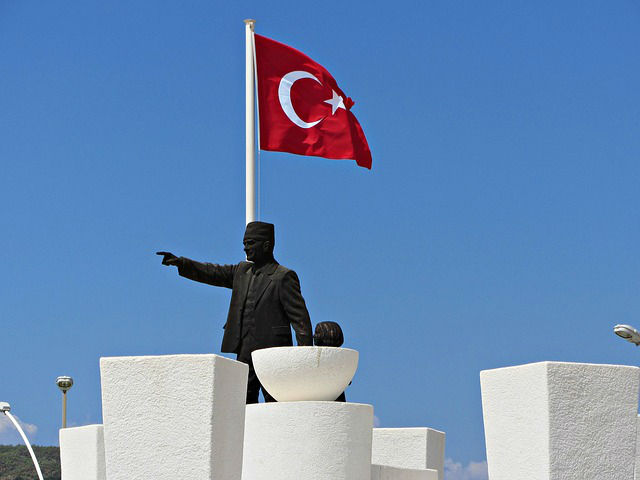 Türkische Flagge auf einem Fahenmast neben einer Statue von Mustafa Kemal Atatürk