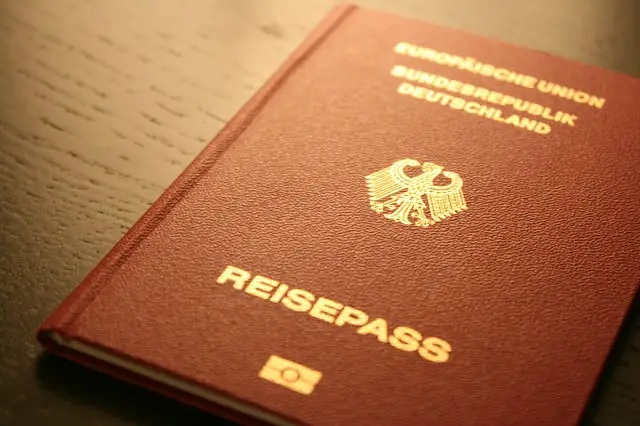 Ein deutscher Reisepass liegt geschlossen auf einem Tisch. Die Hülle ist Rot-Braun und die Schrift in Gold gehalten