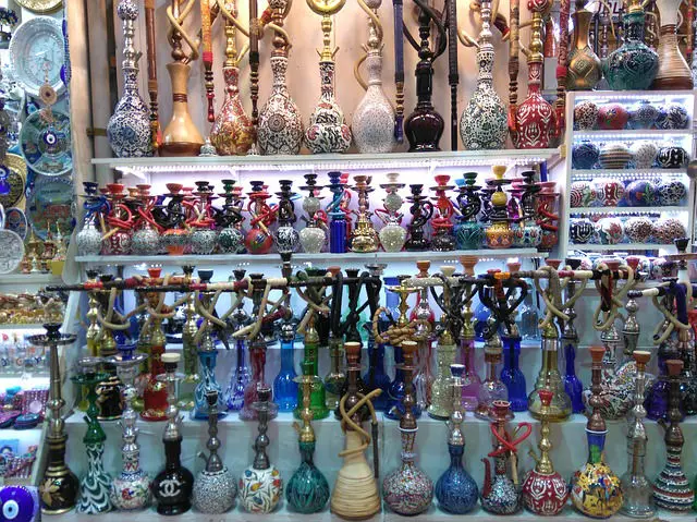 Nargile aus Glas und Porzellangefäßgen für das Wasser in verschiedenen bunten Farben im Regal eines Standes an einem Bazar in der Türkei
