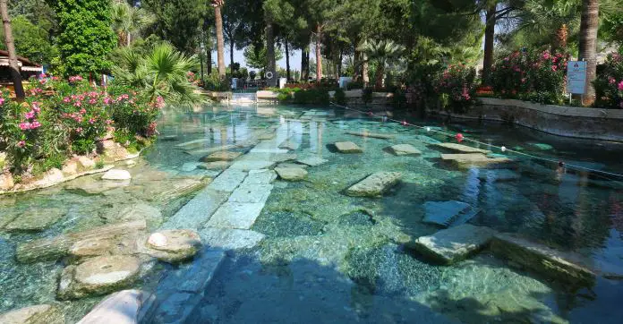 Das türkisblaue, durchsichtige Wasser im Kleopatra Pool. Im Pool sind Mauerreste und Säulen den Ruinen von Hierapolis zu sehen. 