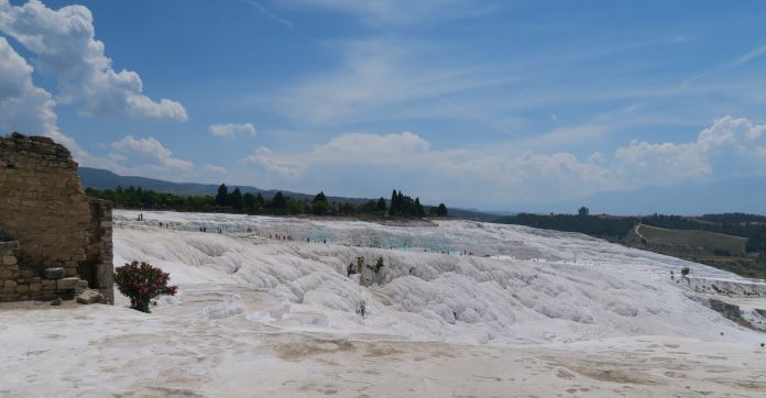 Panoramablick auf die Kalkterrassen von Pamukkale. Blick auf die mit Thermalwasser befüllten Kalkbecken und eine auf der rechten Seite des Bildes zu sehende Mauer. 