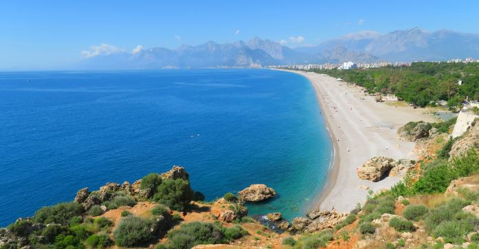 Kilometerlanger und 100 Meter breiter Konyaalti Strand in Antalyas Stadtteil Konyaalti. Im Hintergrund ist das Taurusgebirge zu sehen.