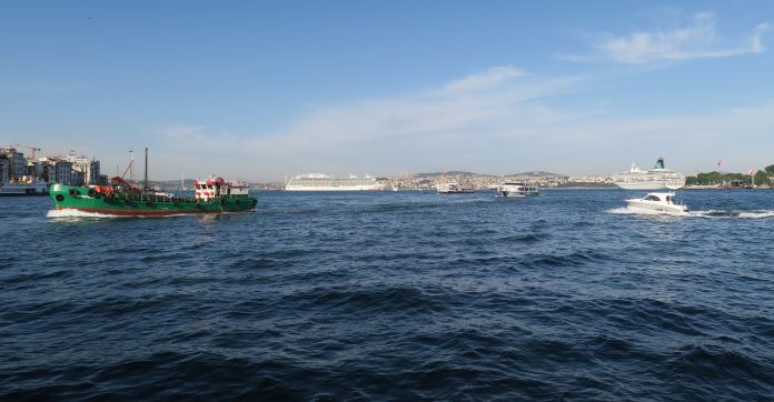 Blick von der Brücke auf den Bosporus Ein mittelgroßes grünes Frachtschiff fährt auf die Bosporusbücke zu. Dahinter ist eine weiße Fähre zu sehen. Ganz im Hintergrund vor der Bosporusbrücke fährt gerade ein Kreuzfahrtschiff Richtung Süden.