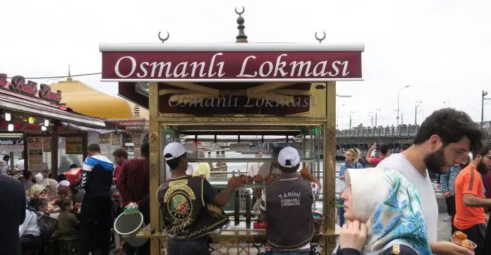 Streetfood neben der Galatabrücke Auf einem Stand mit Essen steht in großer weißer Schrift "Osmanli Lokmasi" und daneben auf einem anderen Stand "Balik Ekmek".