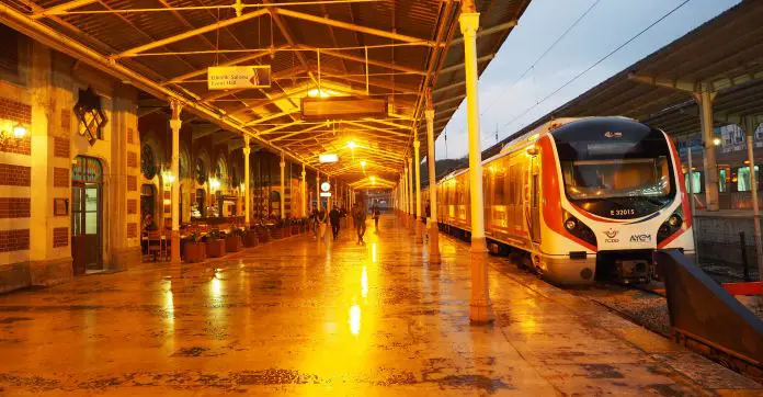 Station der Istanbul Verkehrsbetriebe mit einem eingefahrenen weißen Zug und wenigen Menschen auf dem gut beleuchteten Bahnsteig.