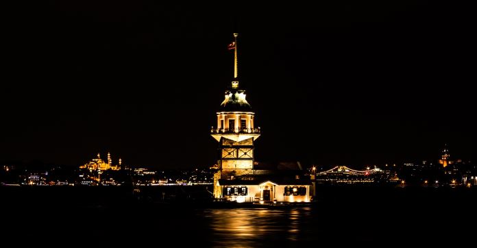 Der hell erleuchtete Leanderturm im Bosporus mit der europäischen Seite von Istanbul im Hintergrund.