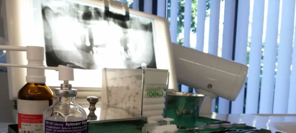 Röntgen Aufnahme eines Zahnarztes in der Türkei. Blickwinkel von einem Behandlungsstuhl. Davor liegt eine Karte einer Auslandskrankenversicherung.