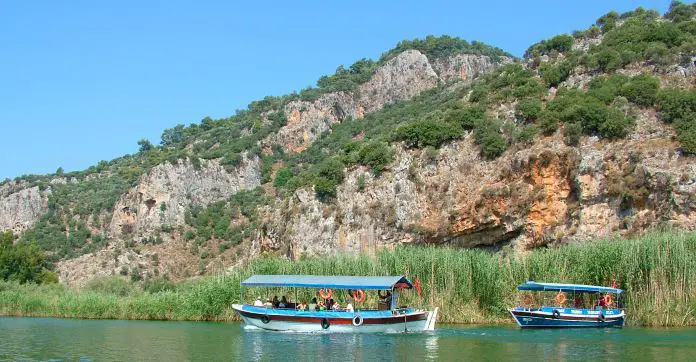 Zwei blau-weiße Boote mit Touristen fahren am Dalyan Fluss.