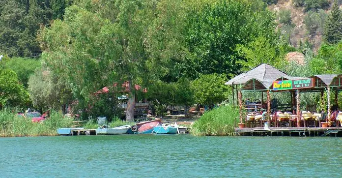 Ein überdachtes Restaurant am Dalyan Fluss im Sommer. Es hat keine Wände. Darin sind viele Touristen zu sehen.