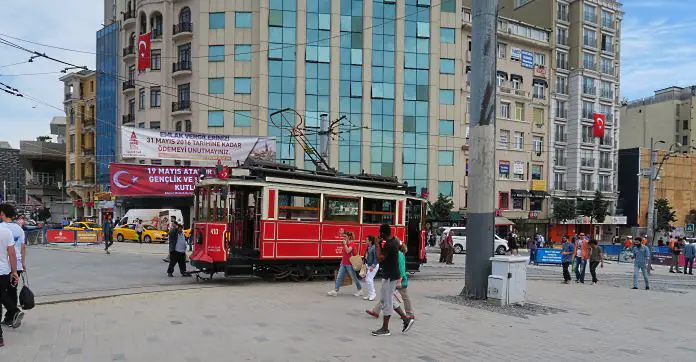 Eine rote Straßenbahn fährt vom Taksim Platz zwischen Fußgängern in die Istiklal Caddesi