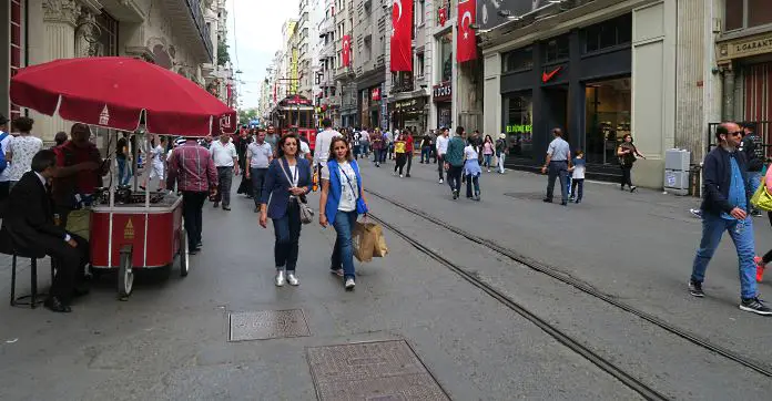 Ein roter Simit Verkaufsstand, Fußgänger und Läden in der Istiklal Caddesi. 