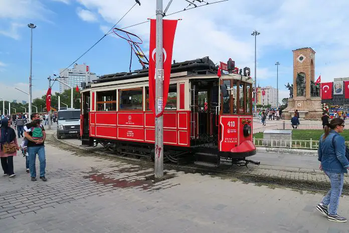 Eine rote Straßenbahn fährt am Taksim Platz an der Haltstelle ein