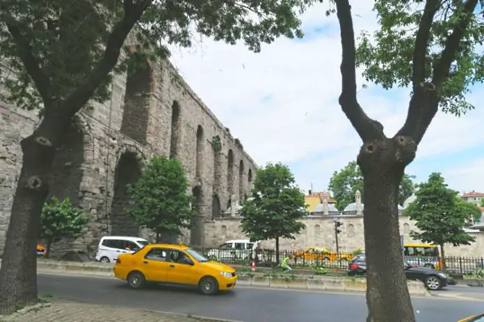 Ein gebes Taxi mit dem Valens-Aquädukt und der mehrspurigen Straße darunter durch.