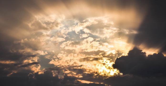 Das rötliche Licht der untergehenden Sonne spiegelt sich am Himmel. Dazwischen ist der blaue Himmel zu sehen. Das Foto vermittelt Hoffnung. 