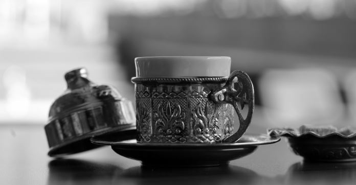 Ein Schwarz-Weiß Bild einer türkischen Kaffeetasse mit einem Messing-Untersetzer. 