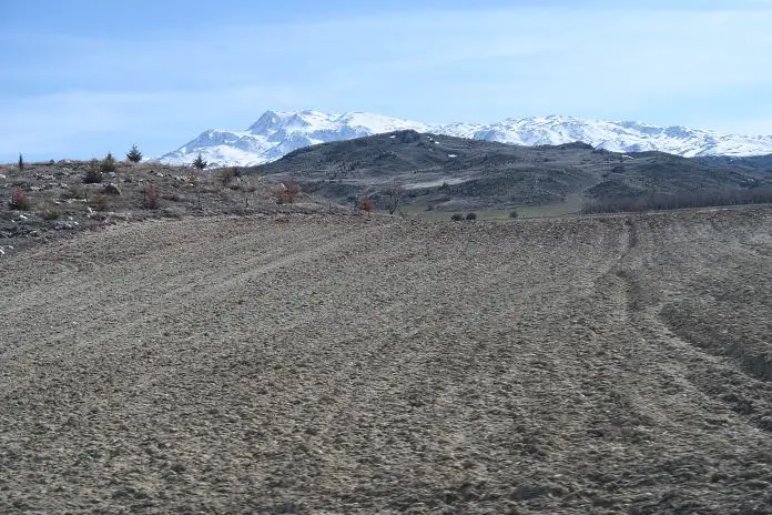 Die schneebedeckten Berggipfel des Taurusgebirges mit einem Acker davor. 