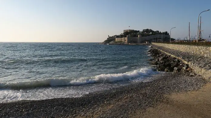 Die Burg auf der Tauben Insel am Hafen von Kusadasi mit dem Strand davor. 