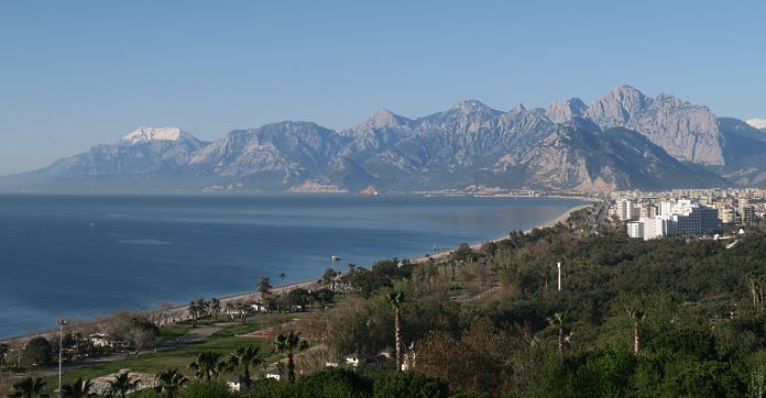 Der Konyaalti Strand in Antalya und das Tauruagebirge im Hintergrund, mit dem Mittelmeer und der Innenstadt von Antalya. 