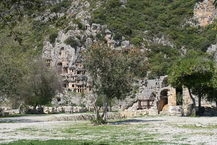 Die Felsengräber und das Theater von Myra. Davor sind bühende Bäume zu sehen. 