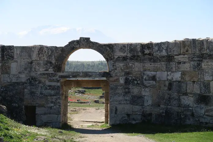 Eines der Stadttore von Hierpolis mit Schneebedeckten Bergen im Hintergrund. 