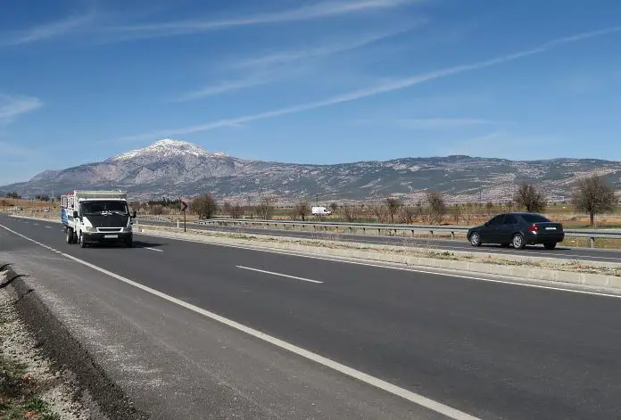 Die Fahrbahn der E-87 Schnellstraße von Pamukkale nach Antalya mit schneebedekcten Bergen im Hintergrund. 