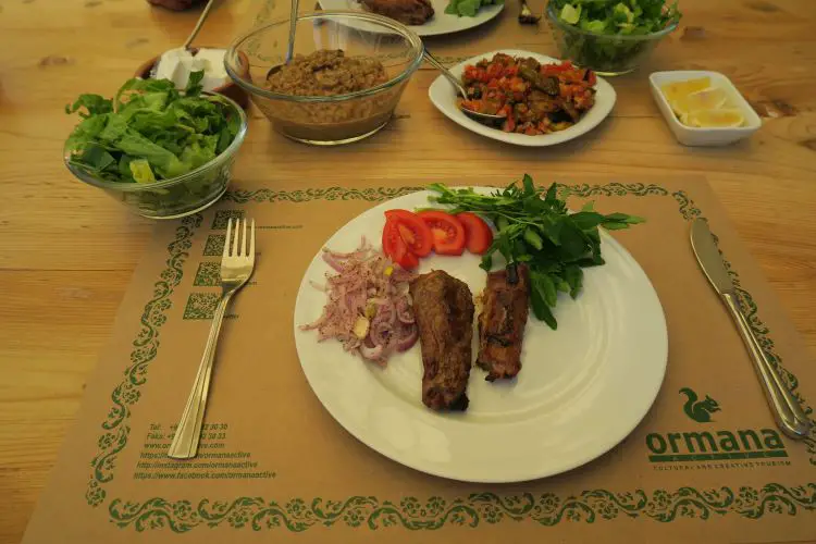 Ein Teller mit einem Stück gebratenen Lammfleisch, Salat und Beilagen. 