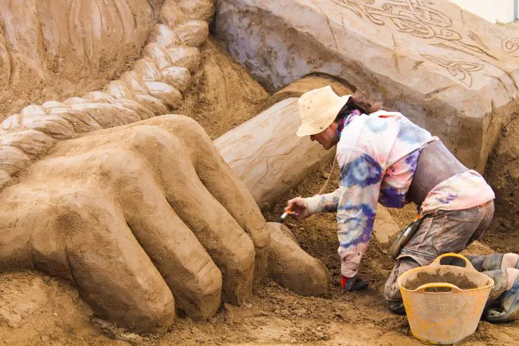 Ein Künstler arbeitet gerade an einer Sandskulptur der nordischen Götterfigur Thor. 