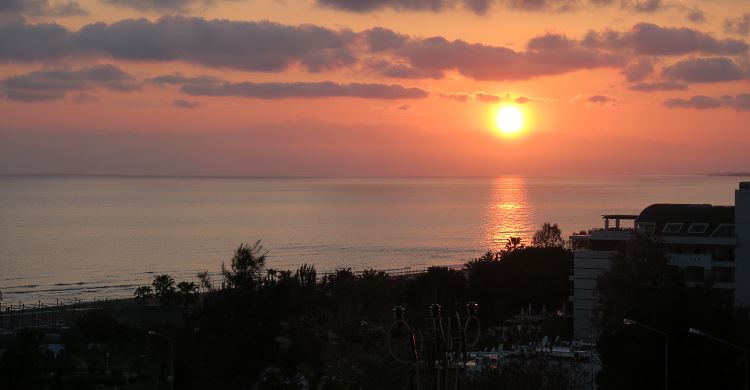 Der rötliche Himmel wärend die Sonne noch knapp am Horizont des Strandes von Side zu sehen ist.