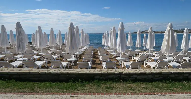 Geschlossene, weiße Sonnenschirme und weiße Sonnenliegen am Strand von Side.