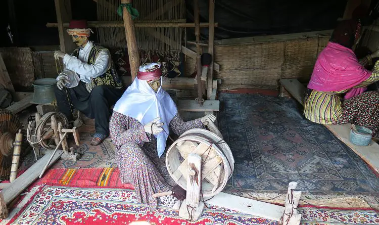 Zwei Figuren sind in einem Yörük-Zelt zu sehen. Eine spinnt gerade Wolle, der andere Arbeitet an einem Tisch. Sie tragen die traditionelle, bunte Kleidung der Yörük-Nomaden. 