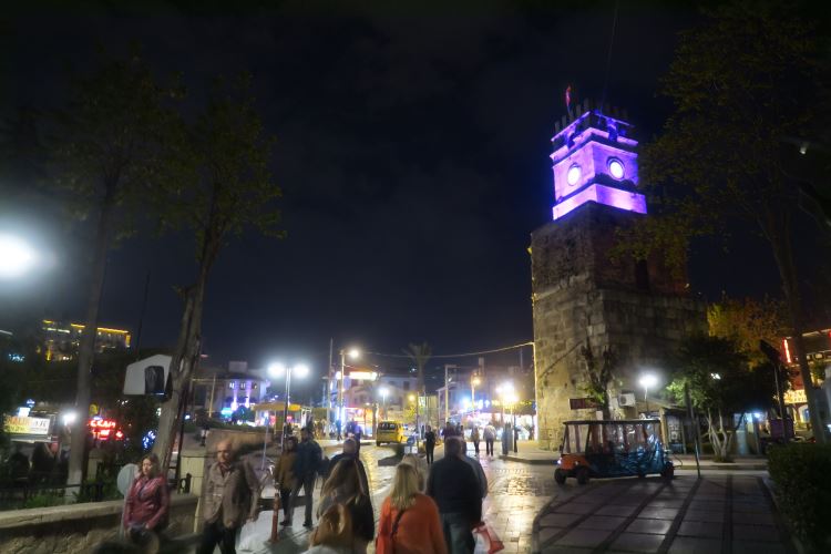 Der Uhrturm von Antalya "Saat Kulesi" während er in der Nacht violett beleuchtet ist.