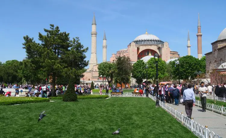 Ein Foto der Hagia Sophia in Istanbul im Mai. Das Gras ist grün, die Sonne scheint und es sind viele Reisende zu sehen. 