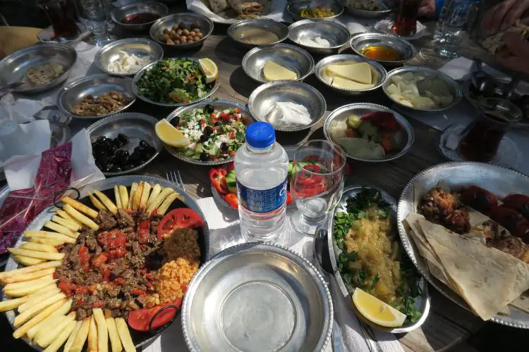 Viele verschiedene türkische Gerichte stehen auf einem Tisch. Darauf liegen Teller mit Salat, Vorspeisen, Hauptspeisen und vielen anderen Essen. 