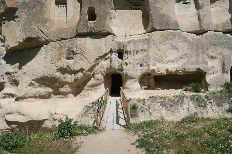 Der Eingang in eine Höhlenkirche in Kappadokien. Er führt über eine kleine Holzbrücke in eine in den Stein gehauene Kirche hinein.