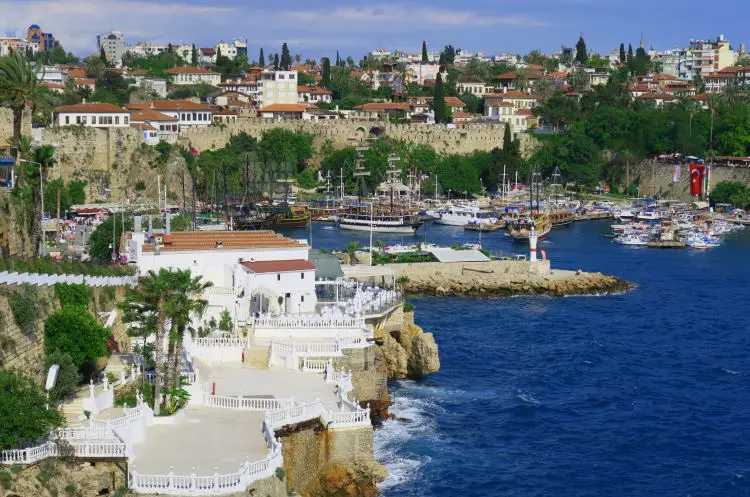 Der wunderschöne Yachthafen mit den Hafenmauern von Antalya, Palmen, Segelschiffen und dem türkisblauen Meereswasser in Antalya. 