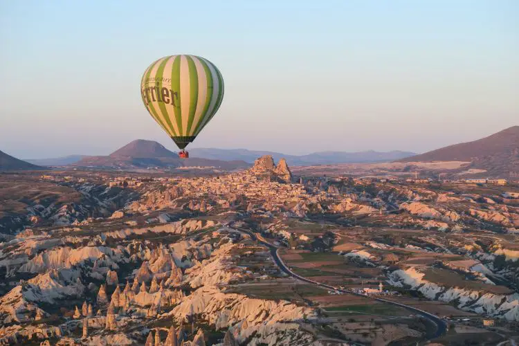 Ein gelber Heißluftballon mit der Festung Uchisar im Hintergrund. Das Bild wurde aus einem Heißluftballon in Kappadokien aufgenommen. 