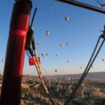 Blick aus dem Korb eines Heißluftballons auf Kappadokien und den Himmel voller anderer Ballone.