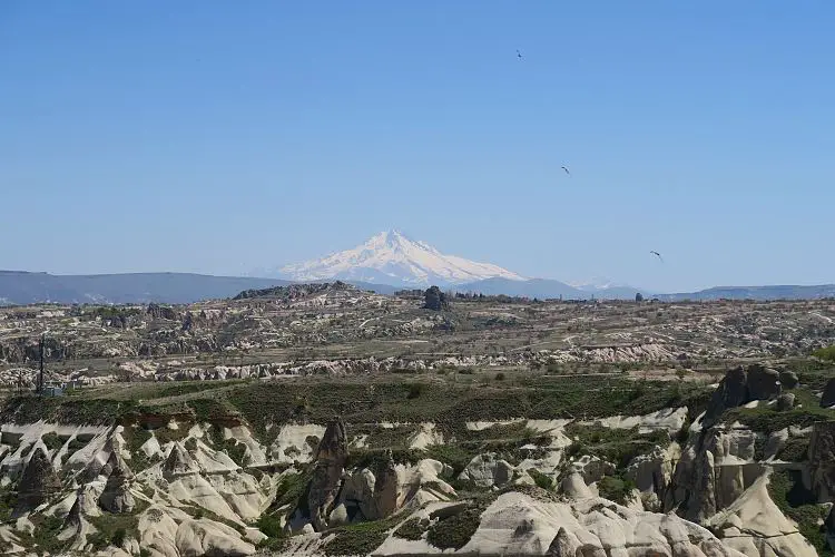 Am 3.917m hohen, freistehenden Vulkan Erciyes Dagi liegt schnee. Davor ist die Landschaft Kappadokiens zu sehen. 