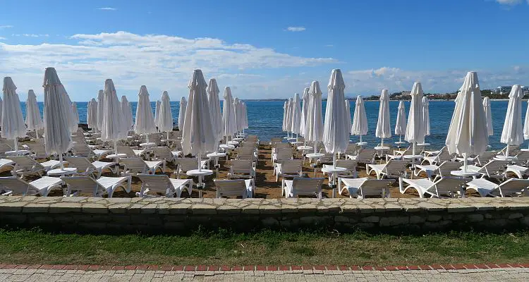 Dutzende, weiße Liegestühle mit weißen Sonnenschirmen stehen am Meer in Side, in der Türkei. 