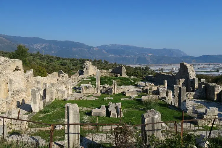 Die Grundmauern einer byzantinischen Kathedrale mit den Bergen und Feldern im Hintergrund. 