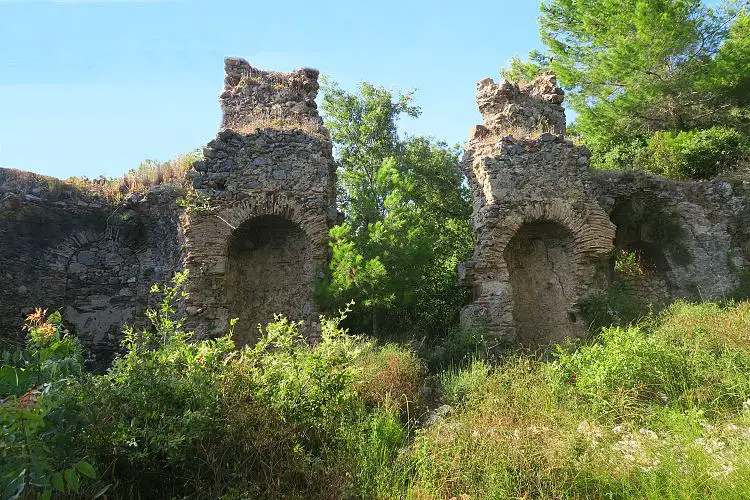 Die Ruinen der byzantinischen Basilika sind mit Baumen und Gras überwachsen. 