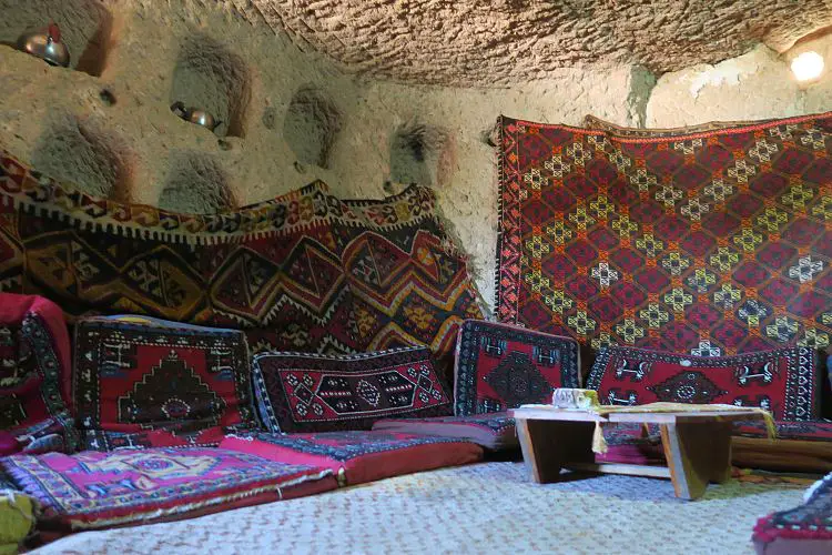 Eine gepolsterte Sitzecke am Boden und ein kleiner Tisch in einem Höhlenhaus.
