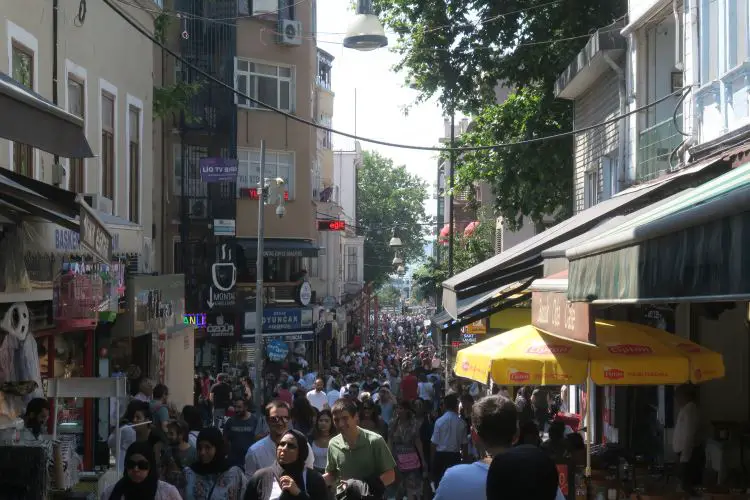 Durch eine schmale Gasse gehen hunderte Menschen. 