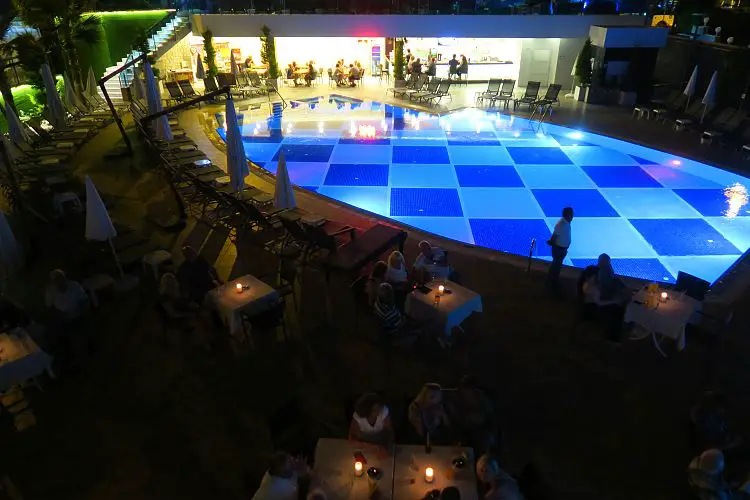 Der Pool mit Tischen und Sesseln am Abend. 