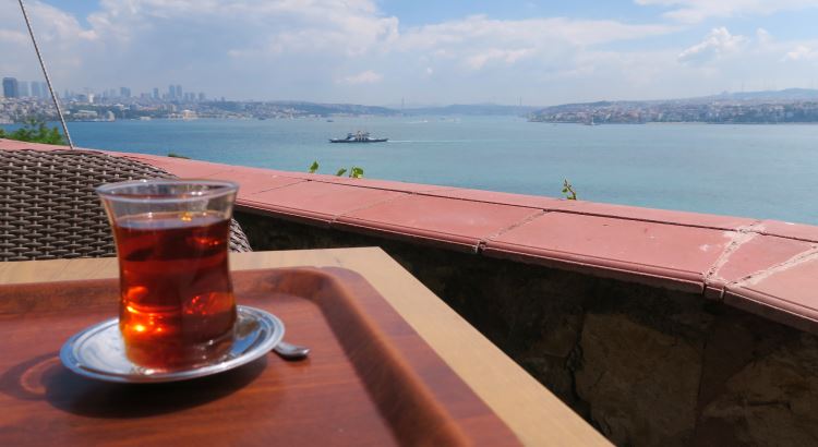 Eine Tasse Cay steht auf einem Tisch in einem Restaurant oberhalb des Bosporus mit Blick auf das Meer und die Stadt. 