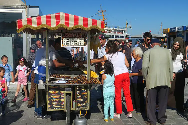 Einwohner von Istanbul stehen neben einem Markstand mit Kastanien.