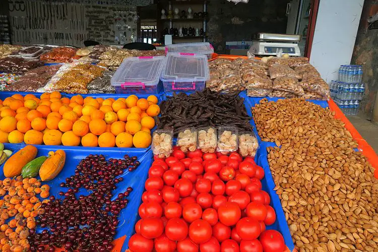 Ein Stand mit Tomaten, Johannisbrot, Orangen, Kirchen und Nüssen.